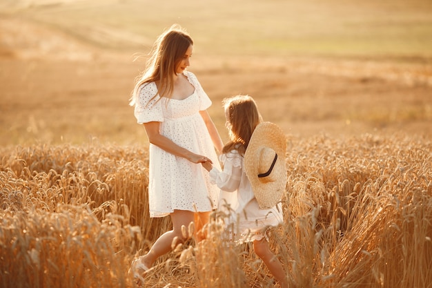 Familia en un campo de trigo. Mujer con un vestido blanco. Chica con sombrero de paja.