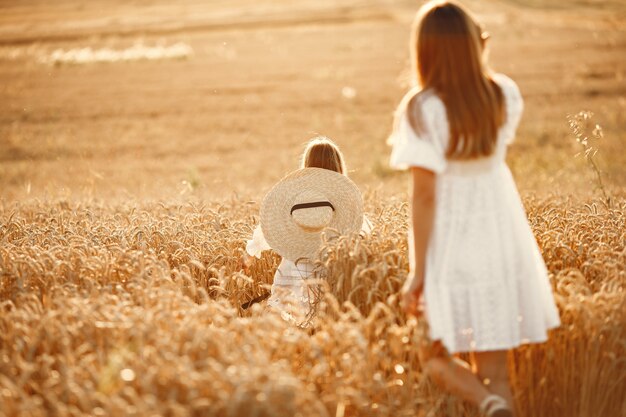 Familia en un campo de trigo. Mujer con un vestido blanco. Chica con sombrero de paja.