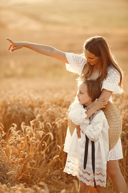 Familia en un campo de trigo. Mujer con un vestido blanco. Chica con sombrero de paja.