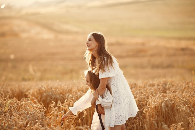 Familia en un campo de trigo. Mujer con un vestido blanco. Chica con sombrero de paja.