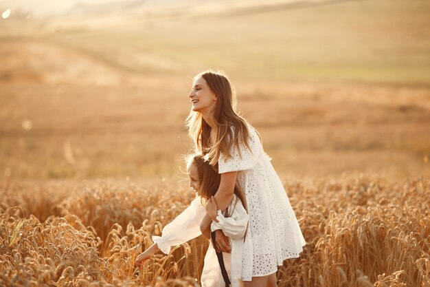 Familia en un campo de trigo. Mujer con un vestido blanco. Chica con sombrero de paja.