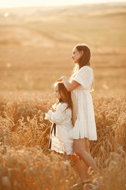 Familia en un campo de trigo. Mujer con un vestido blanco. Chica con sombrero de paja.