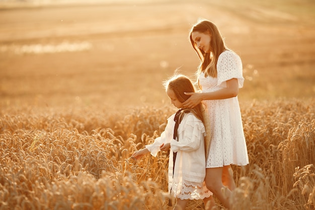 Familia en un campo de trigo. Mujer con un vestido blanco. Chica con sombrero de paja.