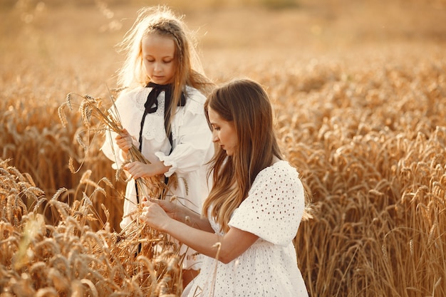 Familia en un campo de trigo. Mujer con un vestido blanco. Chica con sombrero de paja.