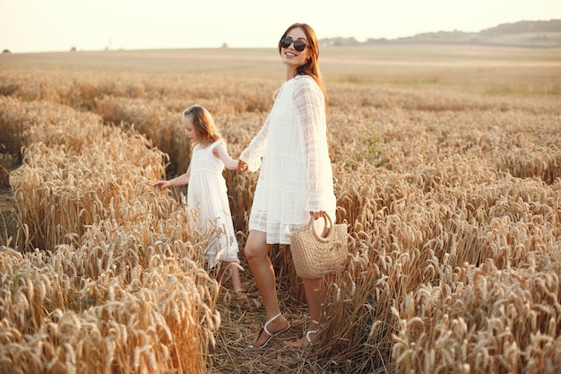 Familia en un campo de verano. Foto sensual. Pequeña niña bonita. Mujer con un vestido blanco.