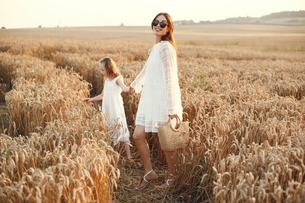 Familia en un campo de verano. Foto sensual. Pequeña niña bonita. Mujer con un vestido blanco.