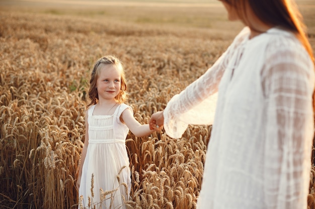 Familia en un campo de verano. Foto sensual. Pequeña niña bonita. Mujer con un vestido blanco.