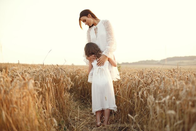 Familia en un campo de verano. Foto sensual. Pequeña niña bonita. Mujer con un vestido blanco.