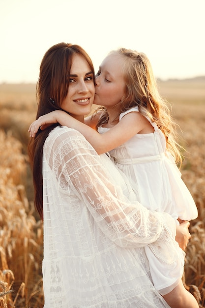 Familia en un campo de verano. Foto sensual. Pequeña niña bonita. Mujer con un vestido blanco.