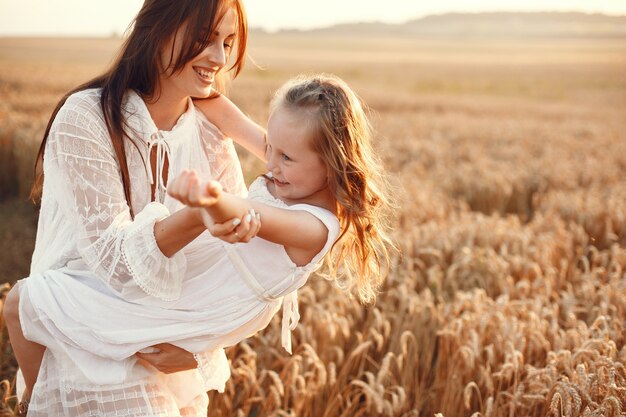 Familia en un campo de verano. Foto sensual. Pequeña niña bonita. Mujer con un vestido blanco.