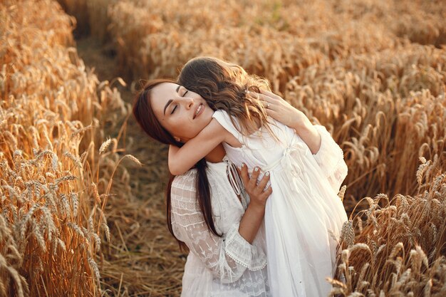 Familia en un campo de verano. Foto sensual. Pequeña niña bonita. Mujer con un vestido blanco.