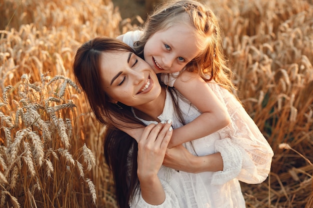 Familia en un campo de verano. Foto sensual. Pequeña niña bonita. Mujer con un vestido blanco.