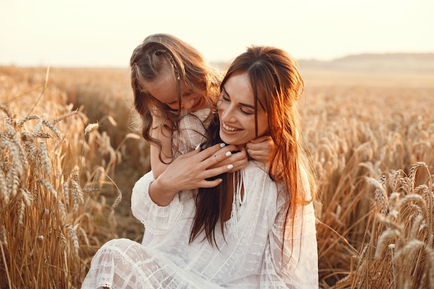 Familia en un campo de verano. Foto sensual. Pequeña niña bonita. Mujer con un vestido blanco.