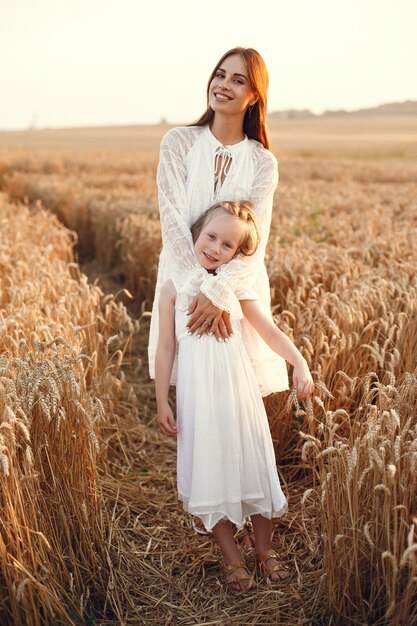 Familia en un campo de verano. Foto sensual. Pequeña niña bonita. Mujer con un vestido blanco.