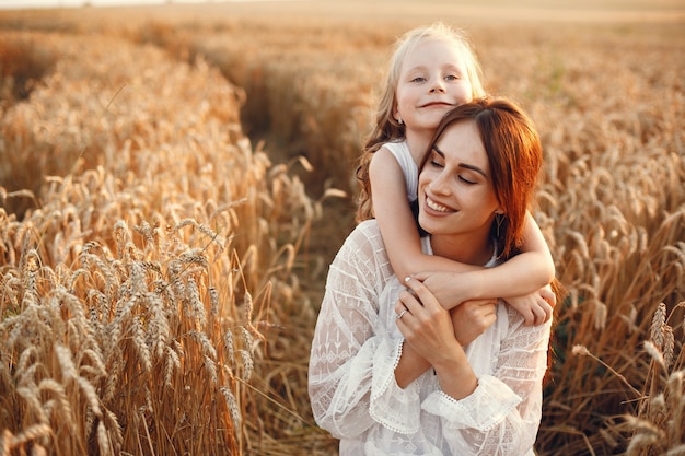 Familia en un campo de verano. Foto sensual. Pequeña niña bonita. Mujer con un vestido blanco.