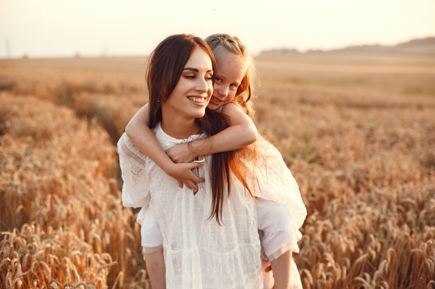 Familia en un campo de verano. Foto sensual. Pequeña niña bonita. Mujer con un vestido blanco.