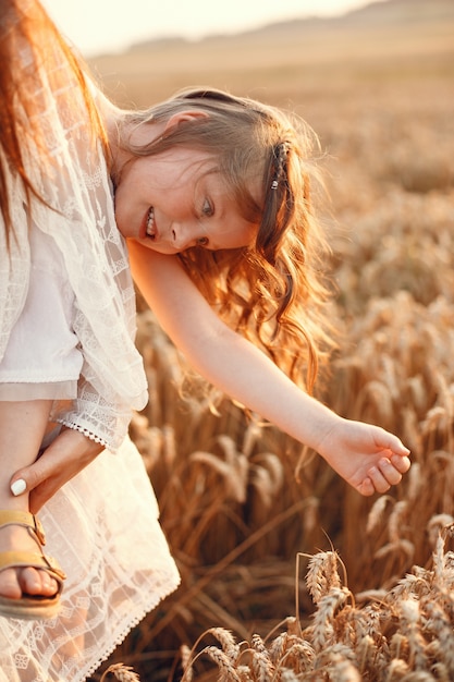 Familia en un campo de verano. Foto sensual. Pequeña niña bonita. Mujer con un vestido blanco.