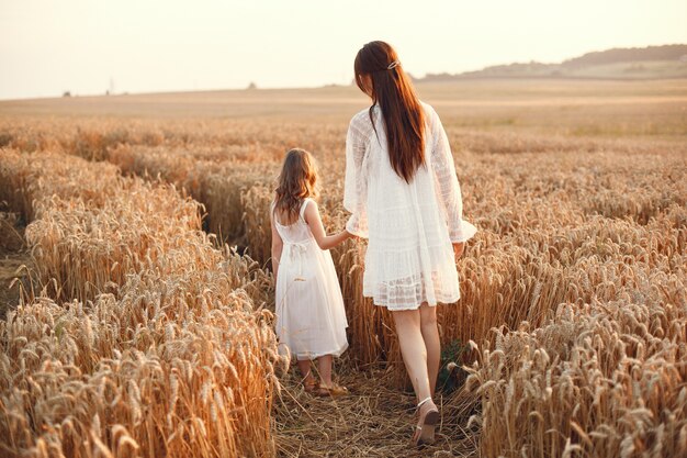 Familia en un campo de verano. Foto sensual. Pequeña niña bonita. Mujer con un vestido blanco.