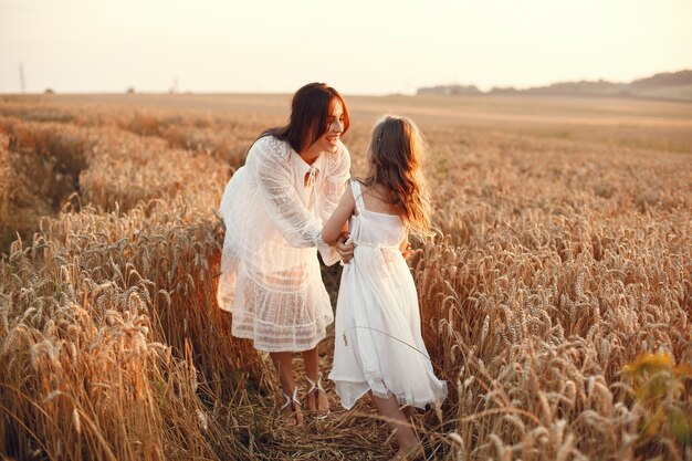 Familia en un campo de verano. Foto sensual. Pequeña niña bonita. Mujer con un vestido blanco.