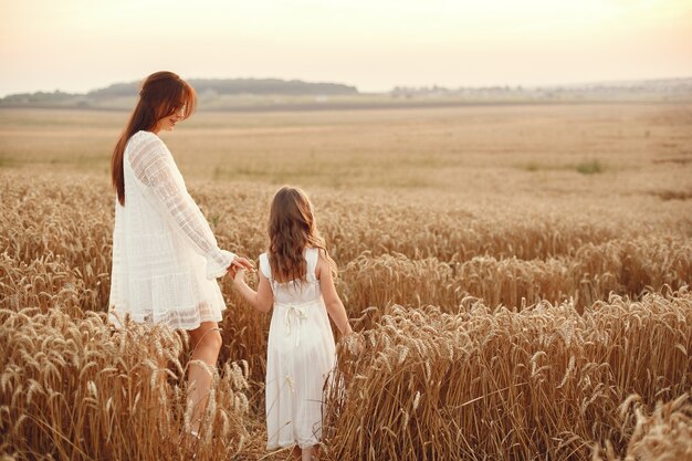 Familia en un campo de verano. Foto sensual. Pequeña niña bonita. Mujer con un vestido blanco.