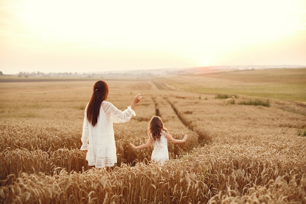 Familia en un campo de verano. Foto sensual. Pequeña niña bonita. Mujer con un vestido blanco.