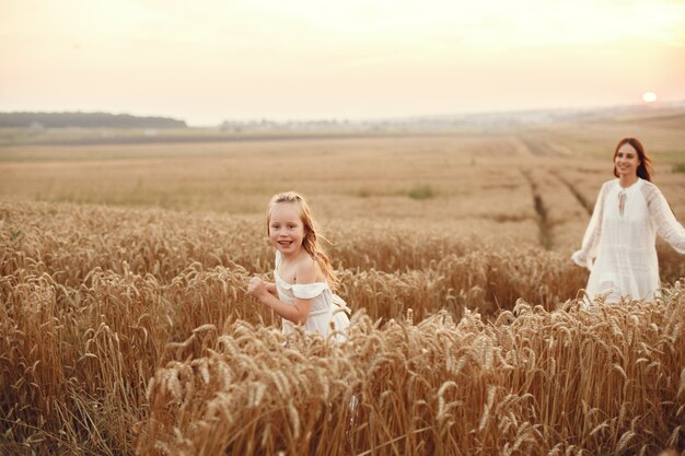 Familia en un campo de verano. Foto sensual. Pequeña niña bonita. Mujer con un vestido blanco.