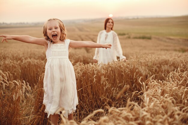 Familia en un campo de verano. Foto sensual. Pequeña niña bonita. Mujer con un vestido blanco.