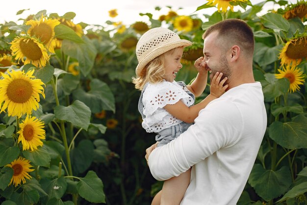 Familia en un campo de verano con girasoles. Padre con camisa blanca. Niño bonito.