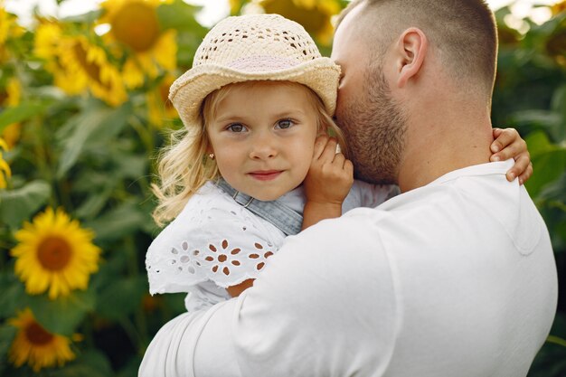 Familia en un campo de verano con girasoles. Padre con camisa blanca. Niño bonito.