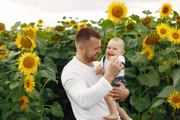 Familia en un campo de verano con girasoles. Padre con camisa blanca. Niño bonito.