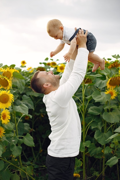 Familia en un campo de verano con girasoles. Padre con camisa blanca. Niño bonito.