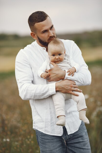 Familia en un campo de verano. Padre con camisa blanca. Linda hija recién nacida.