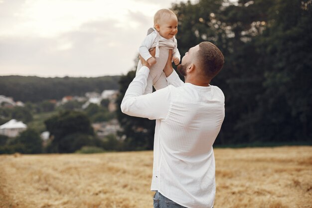 Familia en un campo de verano. Padre con camisa blanca. Linda hija recién nacida.