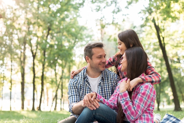 Familia cariñosa que se sienta en el parque que se mira