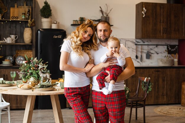 Familia caucásica alegre en apariencia familiar vistiendo camiseta blanca y pantalón rojo. Padre con bebé.
