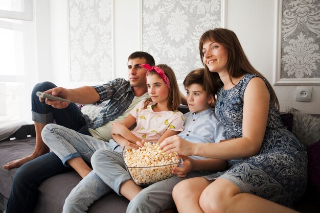 Familia comiendo palomitas mientras ve televisión en casa