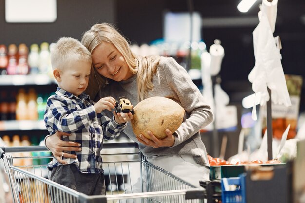 Familia comprando comestibles. Madre en suéter gris.