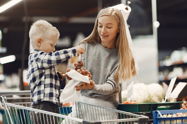 Familia comprando comestibles. Madre en suéter gris.