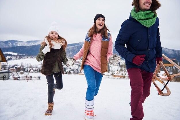 Familia corriendo por las colinas nevadas