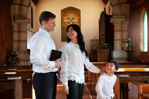 Familia cristiana feliz de tiro medio en la iglesia