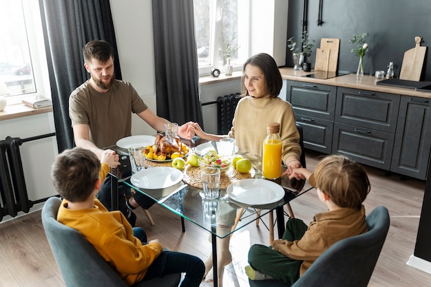 Familia cristiana de tiro medio comiendo juntos