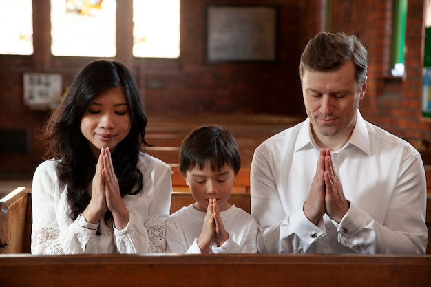 Familia cristiana de tiro medio rezando en la iglesia