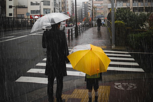 Foto gratuita familia cruzando una calle en un día lluvioso