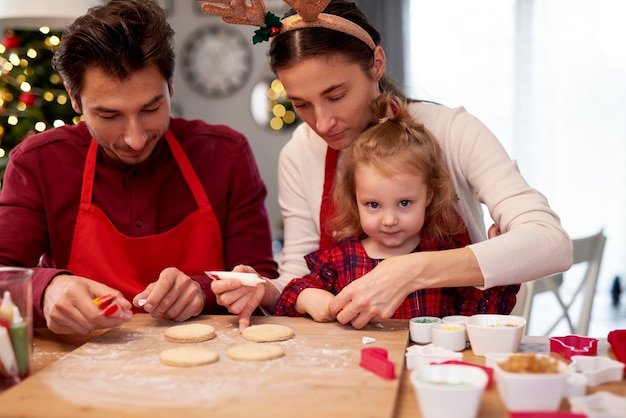 Familia decorando galletas de Navidad en la cocina