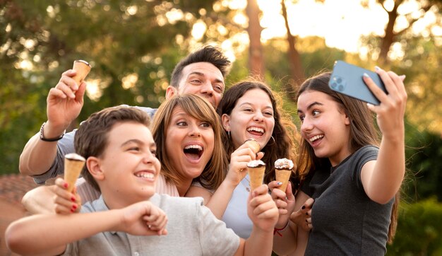 Familia disfrutando de un helado juntos al aire libre y tomando selfie