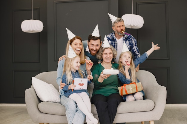 Familia y dos de sus hijas celebran cumpleaños Dos hombres, dos mujeres y dos niñas está sentado en un sofá y posando para una foto