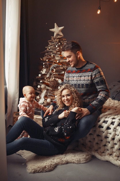 Familia elegante sentada en casa cerca del árbol de navidad