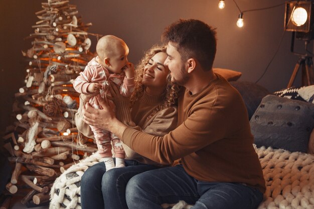 Familia elegante sentada en casa cerca del árbol de navidad