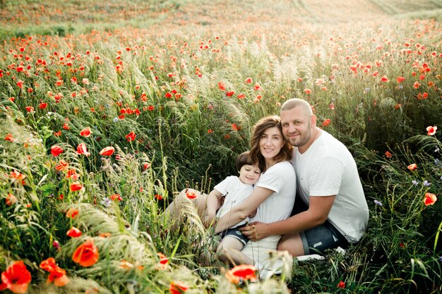 Familia encantadora se sienta entre las amapolas