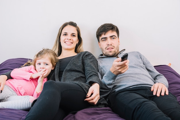 Familia feliz acostado en la cama viendo la televisión